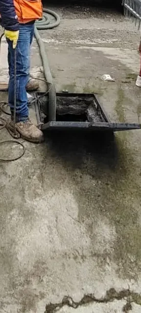 Operario de Saneamiento RAMGL supervisando la limpieza de una cisterna residencial mediante un sistema de succión conectado a un camión cisterna especializado.