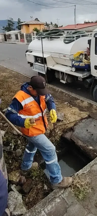 photo-hero-15 Técnico de Saneamiento RAMGL trabajando en limpieza de pozos sépticos en calderón a pie de calle, con un camión cisterna de apoyo equipado para limpieza y mantenimiento.